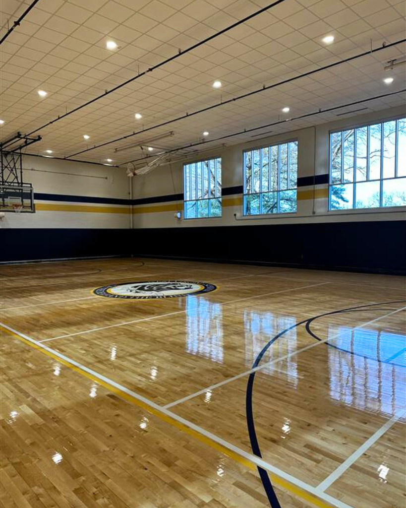An overview of the gymnasium featuring the updated flooring and blue and yellow stripe going around the perimeter of the gymnasium. 