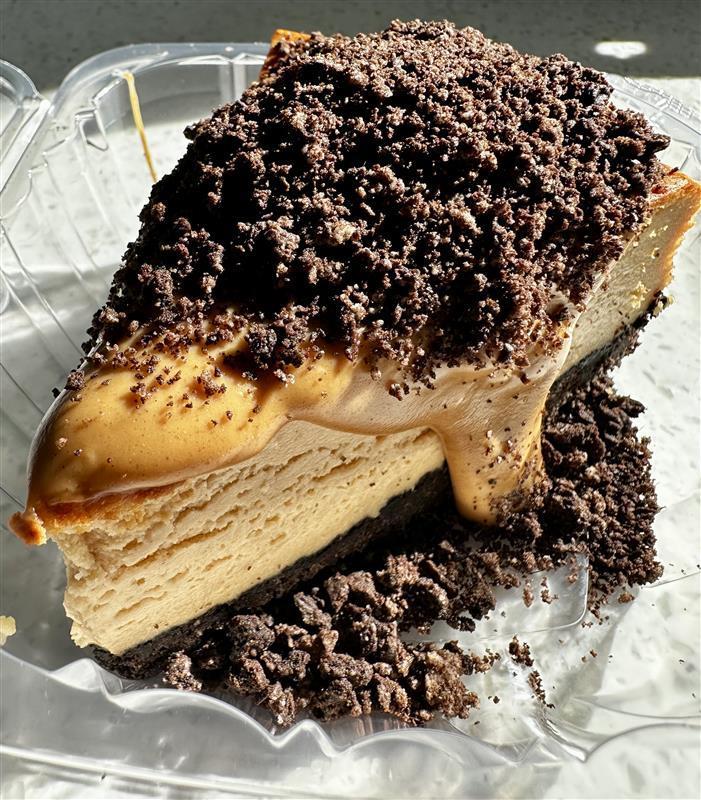Peanut Butter Oreo Cheesecake. A slice of peanut butter cheesecake with chocolate Oreo crumbles on top.