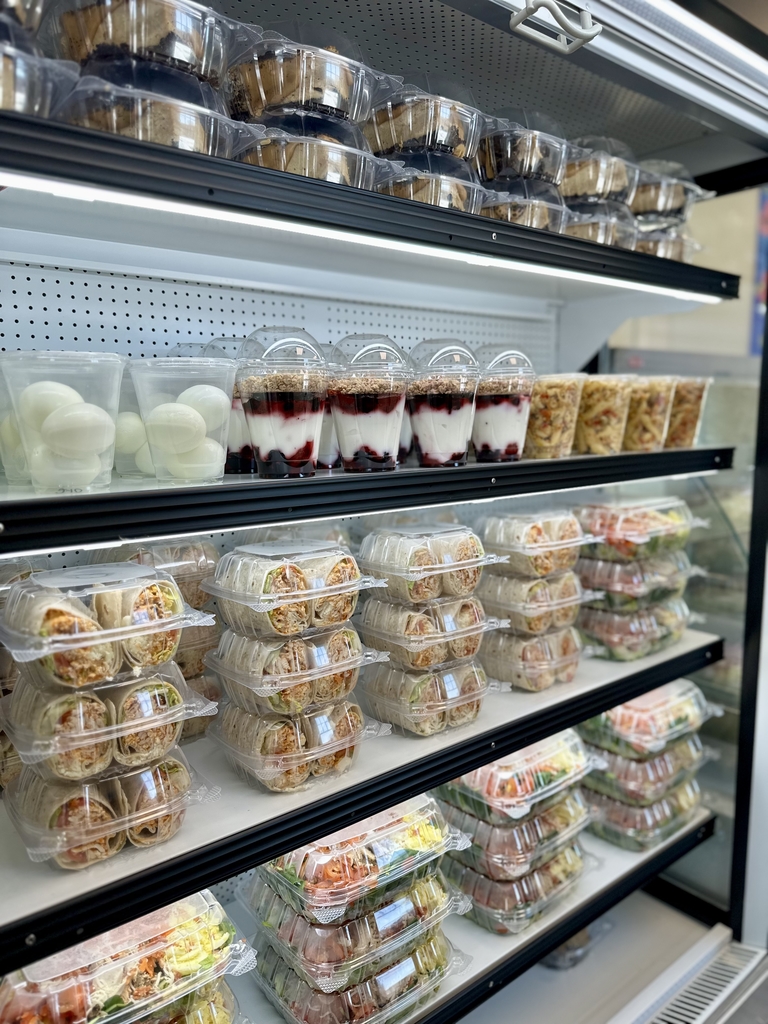 A refrigerator featuring this week's menu items - yogurt parfait, pasta salad, chef salad, and buffalo chicken wraps.