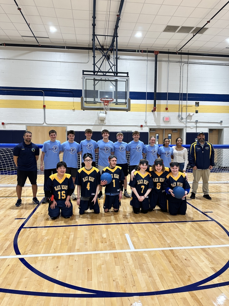 Frankfort athletes wearing matching blue shirts stand in the backrow, while WVSDB athletes wearing their blue and gold jerseys pose in front of the Frankfort athletes. Male goalball coaches stand on each side of the group of athletes.