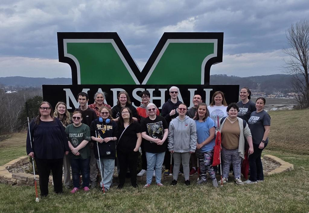 WVSDB students, educators, and staff stand in front of a large, green "M" that stands for Marshall University. 