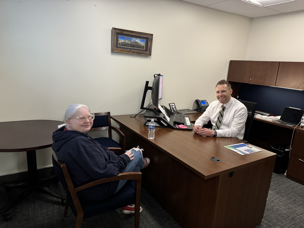 A female WVSDB student looks back and smiles for the camera, while a male WVDE employee sits at his desk and smiles for the camera. 