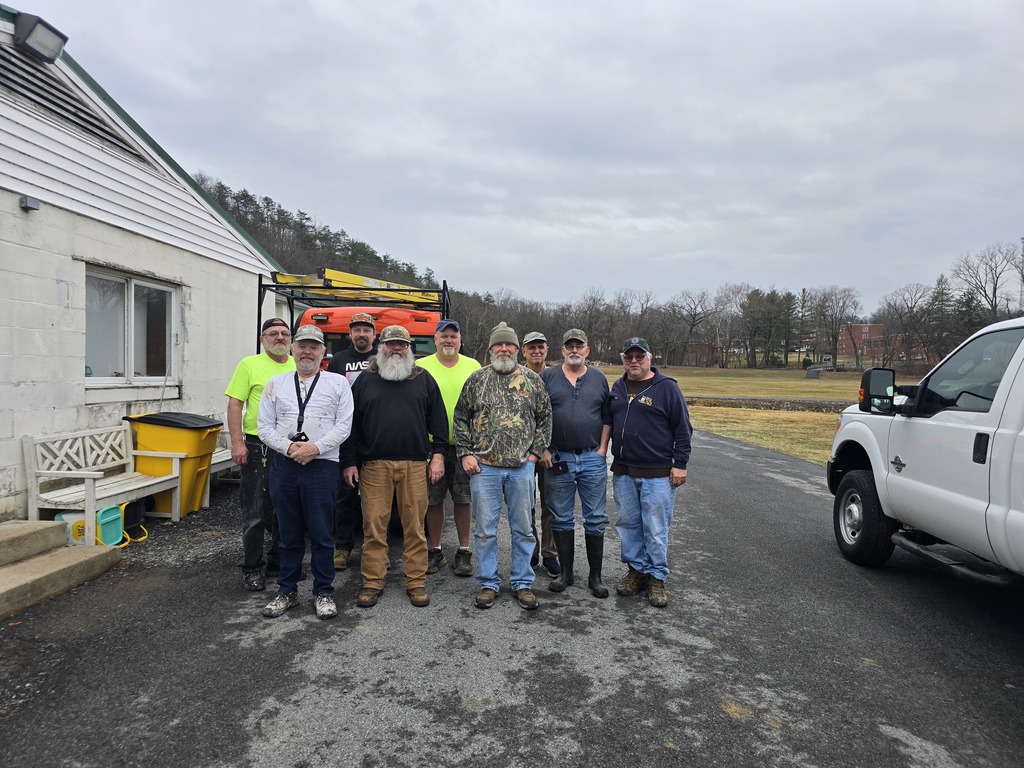 A group photo of the WVSDB maintenance team. A group of men stand side by side outside of the maintenance building. 