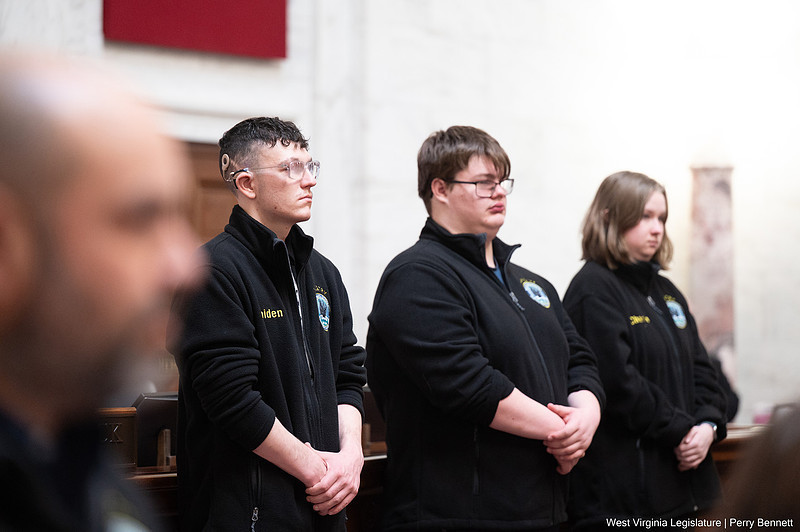 Three WVSDB students stand side by side wearing matching black, fleece jackets with their hands in front of them.