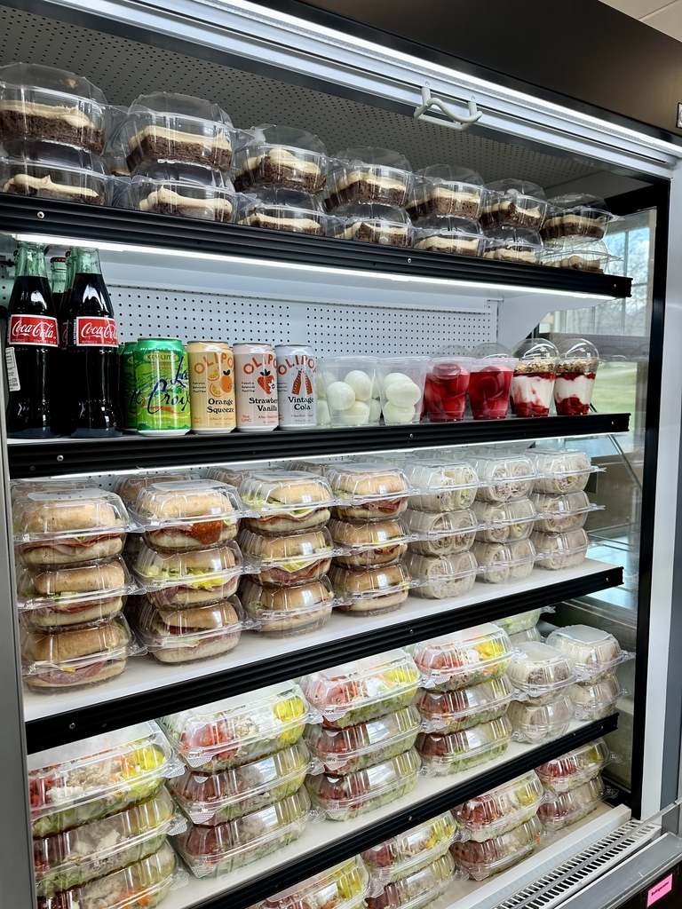 Refrigerator stocked with sandwiches, salads, wraps, yogurt parfaits, and beverages. 
