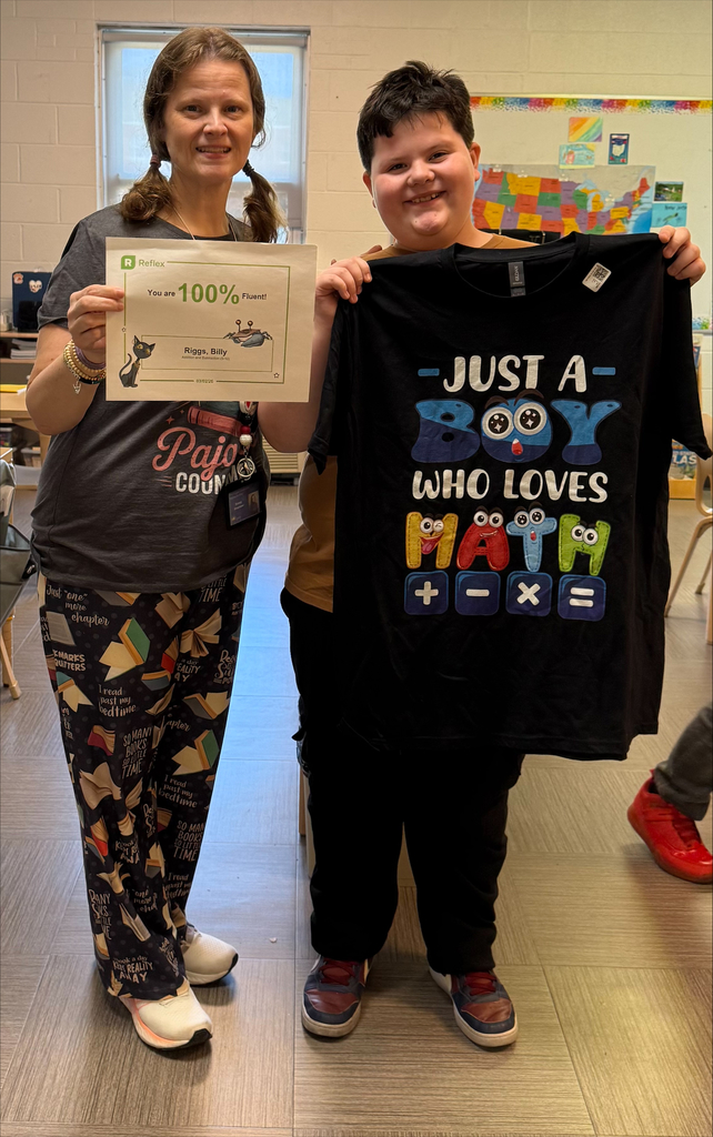 Billy, a male WVSDB student holds up a black shirt with the text "Just a boy who loves math." Beside him is Mrs. Shoemaker, a female WVSDB teacher who is holding up a certificate. 