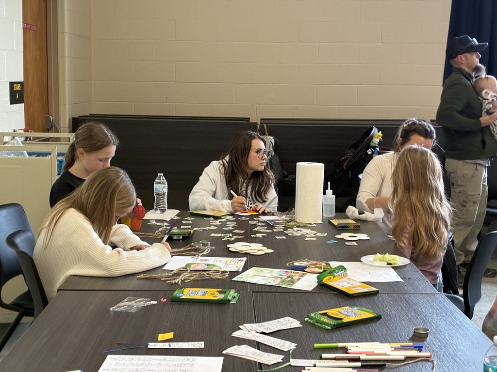 Deaf Social participants are seated at a table doing crafts using markers and colored pencils.