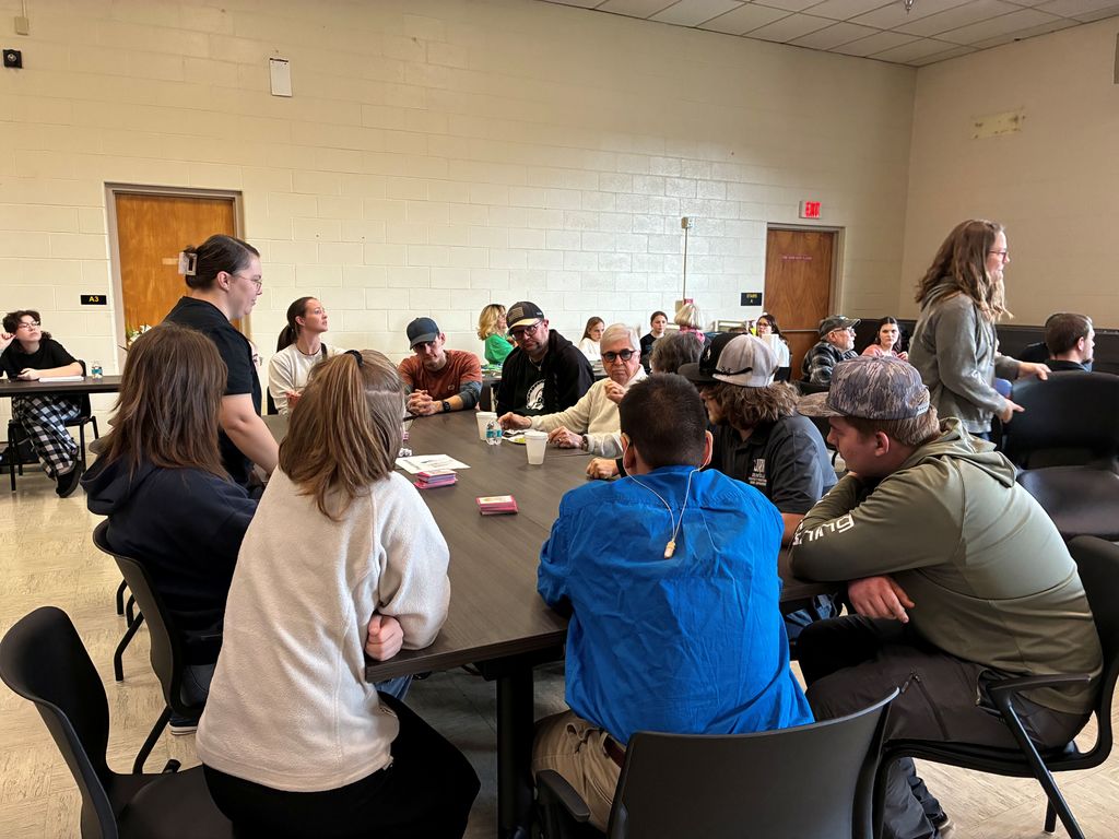Deaf Social participants are seated side-by-side at a table mingling among one another.