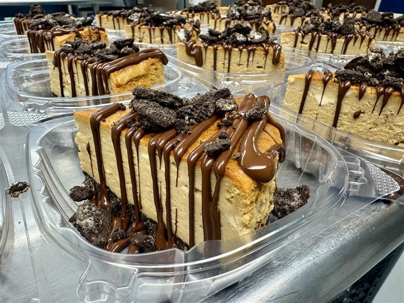 Peanut Butter Oreo Cheesecake. A slice of peanut butter cheesecake with chocolate Oreo crumbles on top.