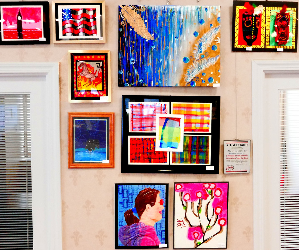 A beige-colored wall filled with colorful works of multimedia art.