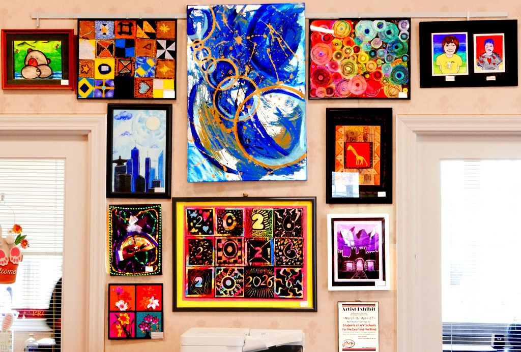 A beige-colored wall filled with colorful works of multimedia art.