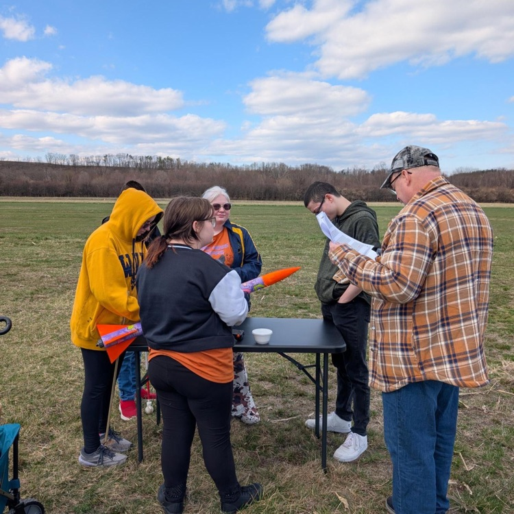 Rocketry club members are gathered around a table as they work on assembling their rocket.