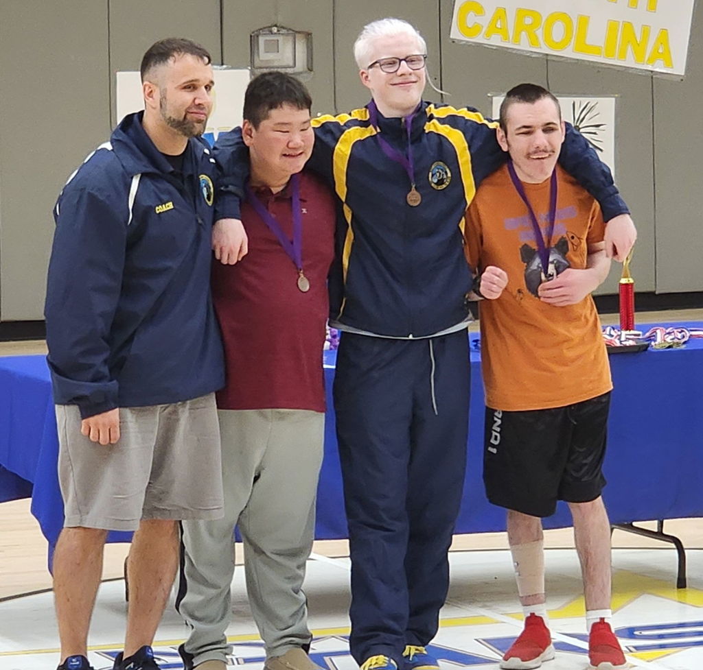 Male Goalball players stand side-by-side with Coach Smith.