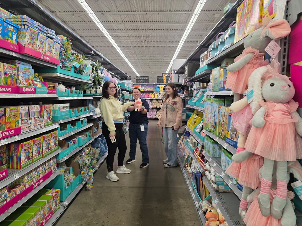 Female students and a female WVSDB representative smile and pose with an Easter holiday toy.