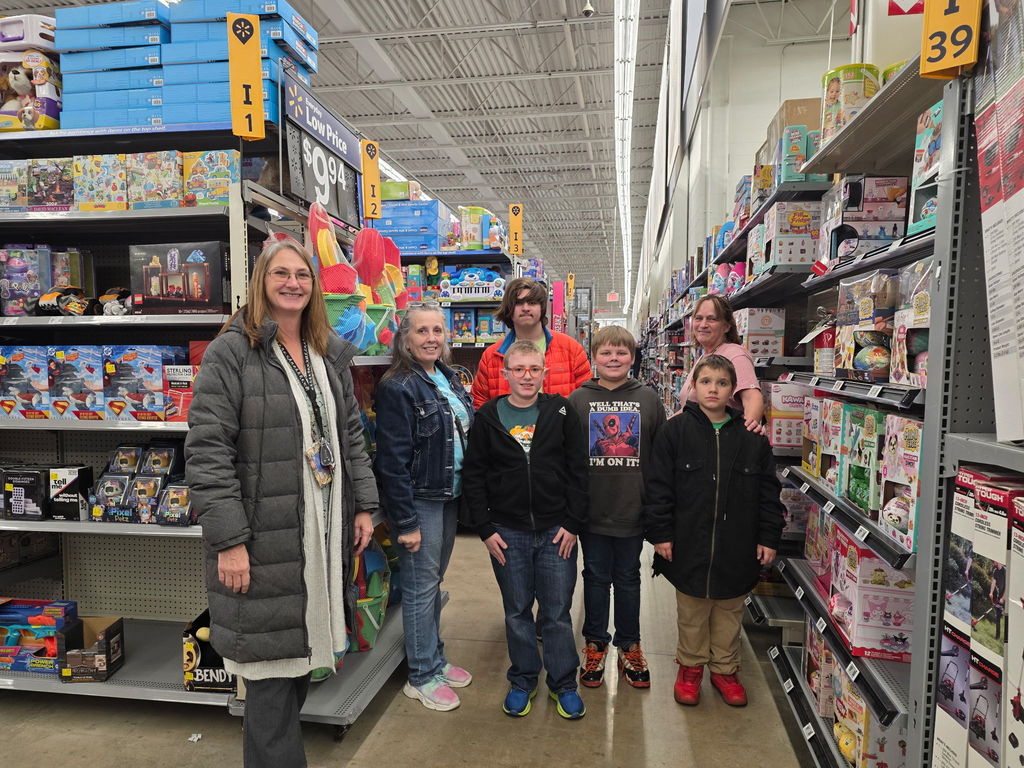 A group of students stand side-by-side, along with WVSDB representatives in a toy aisle at Walmart. 