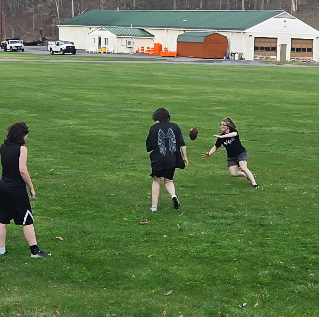 A group of female students rush to grab a football.