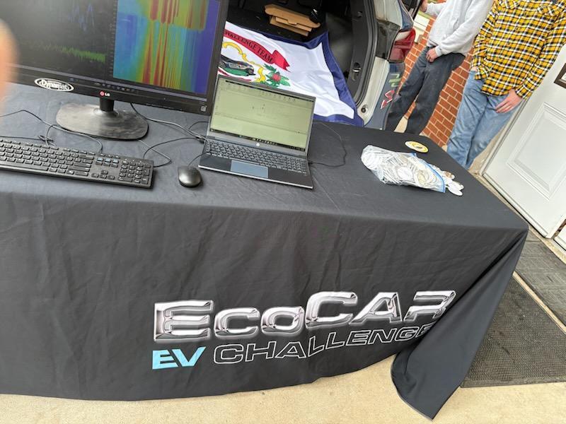 ECOCar tablecloth with computers and laptops sitting on top of the tablecloth.