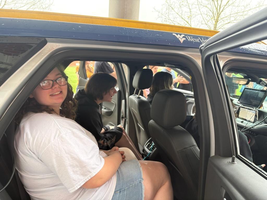 A female student in the backseat of the ECOCar smiles at the camera.