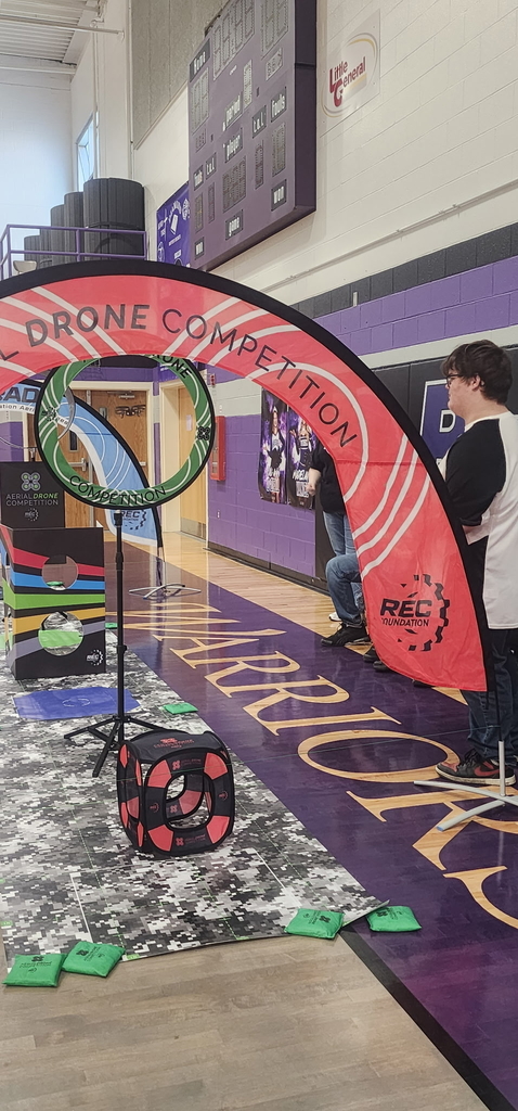 A male drone team member looks out to the drone course that features green and red-colored obstacles.