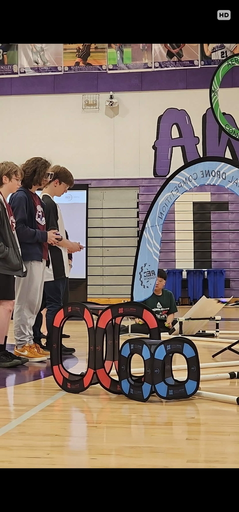 Drone team members wearing safety goggles hold their controllers in their hands as they compete in the competition.