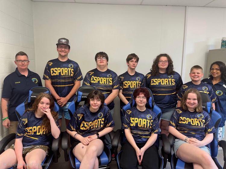 A group photo of the Esports team and their coaches. 2 rows of team members dressed in matching blue and gold jerseys.