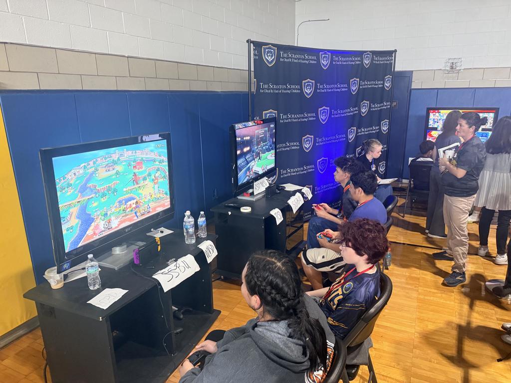 Esports players sitting in pairs of two compete against one another as they look at the screen in front of them.