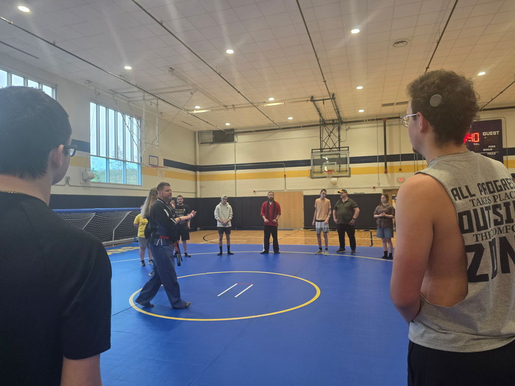 Students standing in a circle around the Martial Arts instructors and the ASL interpreter.