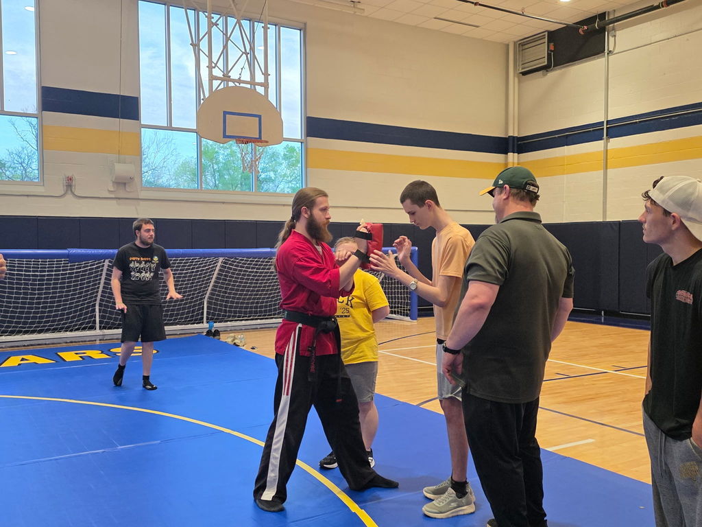 A Martial Arts instructor stands across from a student as they practice self-defense techniques.