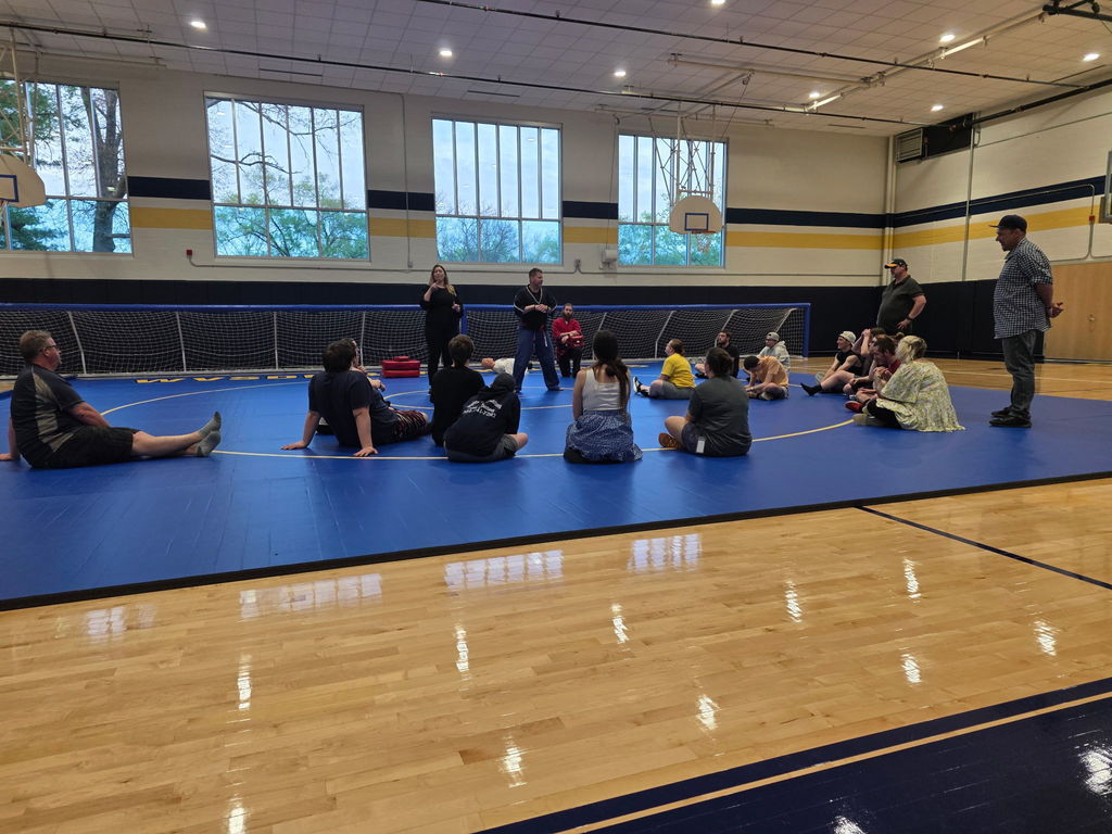 Students seated in a circle around the Martial Arts instructors and the ASL interpreter.