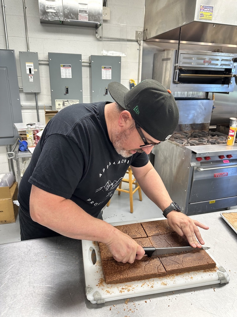 Chef Brian Olden looks down as he cuts chocolate brownies into large squares.