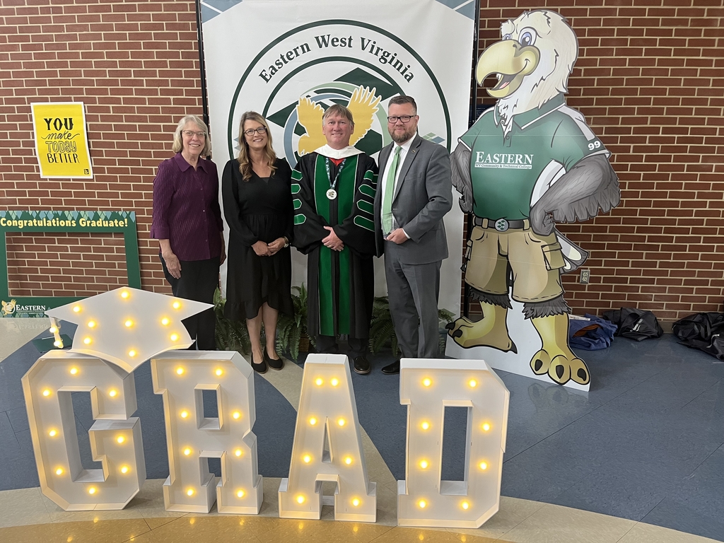 Two female interpreters, Ms. Jennifer Casto and Mrs. Shari Loar stand alongside Dr. Striplin, who is dressed in graduation regalia. To his left, is Superintendent Burch who proudly holds the Apex award.