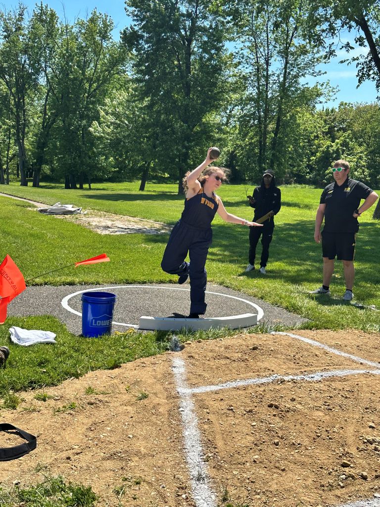 A female athlete, Brooklyn, gets in position to throw a shotput during a field event.