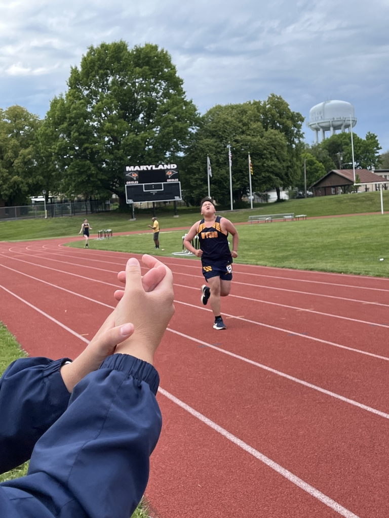 A male athlete, Tristian, wearing a blue and yellow uniform runs hard on a red-colored track.
