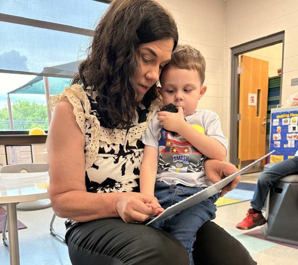Ms. Wendy Bailey, WVSDB Outreach VI Coordinator sits with a male VI student. She assists him while holding his hand to feel the Braille dots spelling out his name.