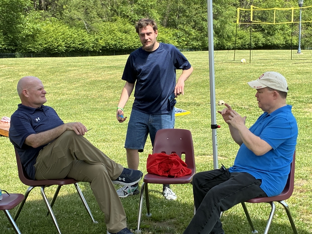 Male participants are seated and are using American Sign Language (ASL) to communicate with one another.