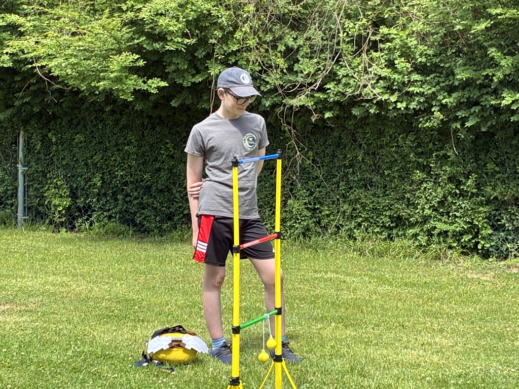 A male participant, CJ, stands and waits his turn during an outdoor game.