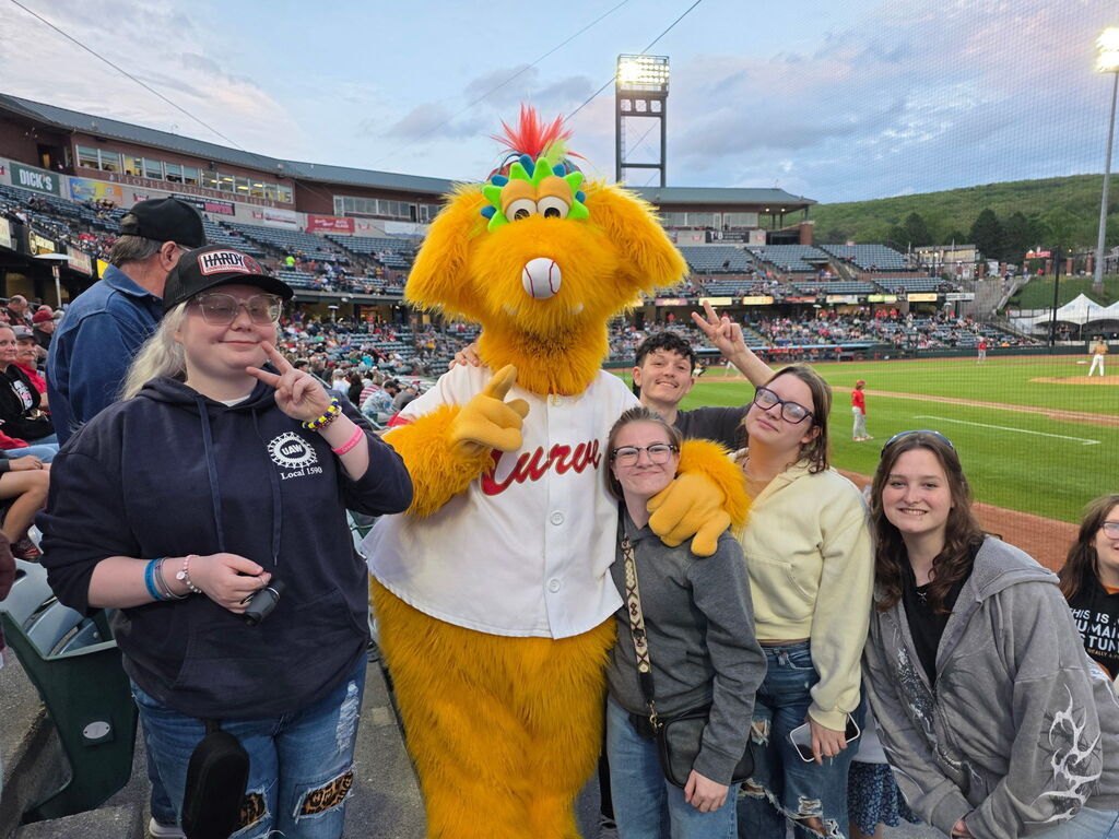 Female students pose with an orange Altoona Curve mascot that is wearing a white baseball jersey.