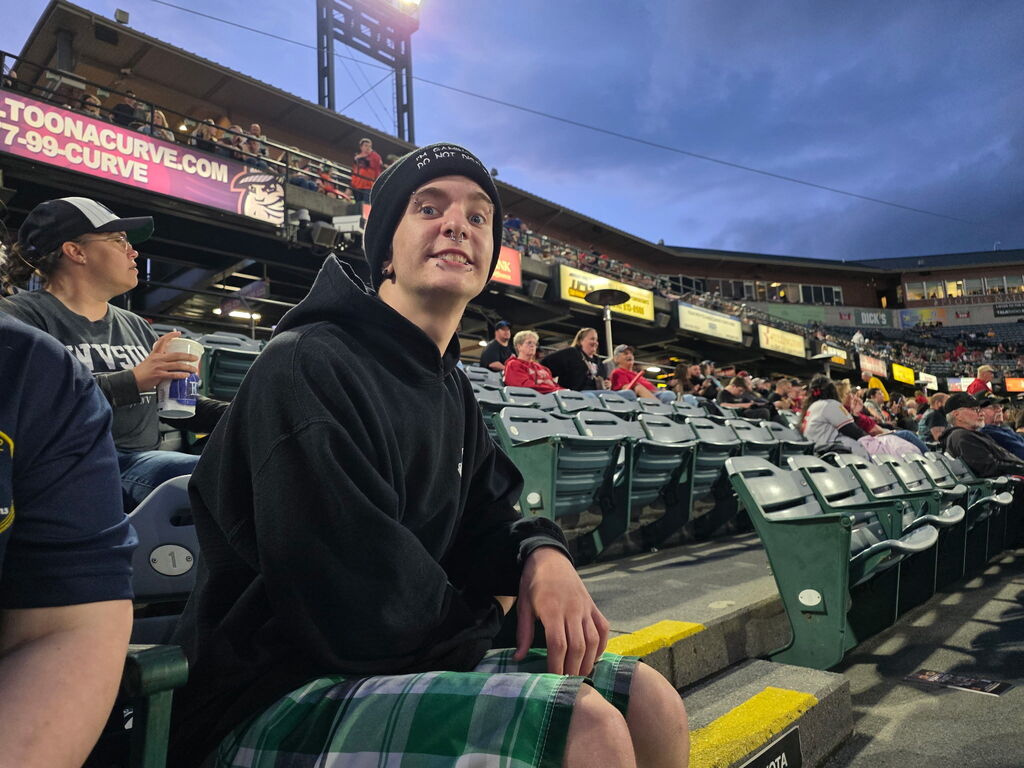 A male student, James is seated in the stadium bleachers, smiles for the camera.
