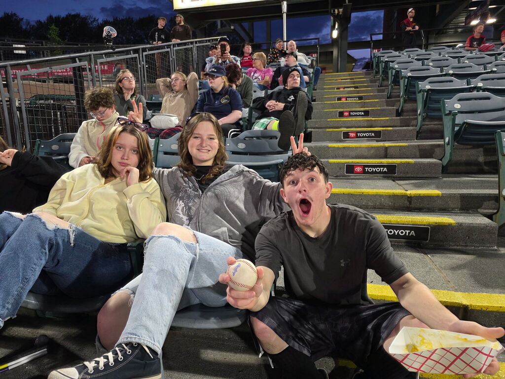 Three WVSDB students pose excitedly for the camera while they are seated in the stadium bleachers.
