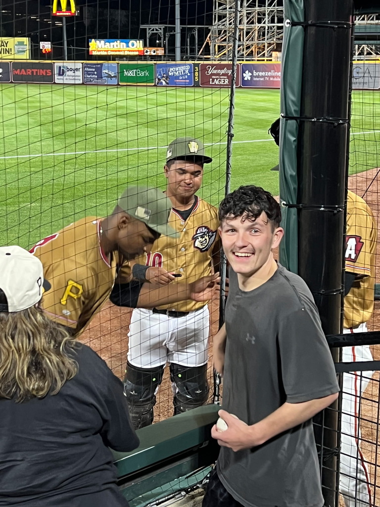 A male student, Raiden smiles excitedly as he gets autographs from baseball players.