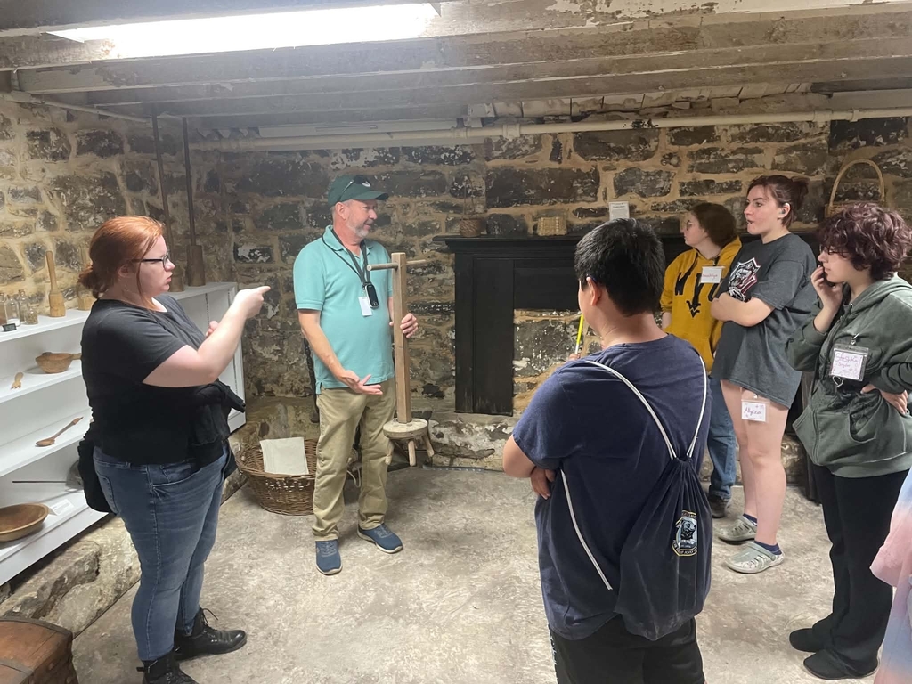 Students gathered in a group as they look at a female interpreter who uses American Sign Language (ASL) to communicate what the Evergreen Heritage Center is speaking about.