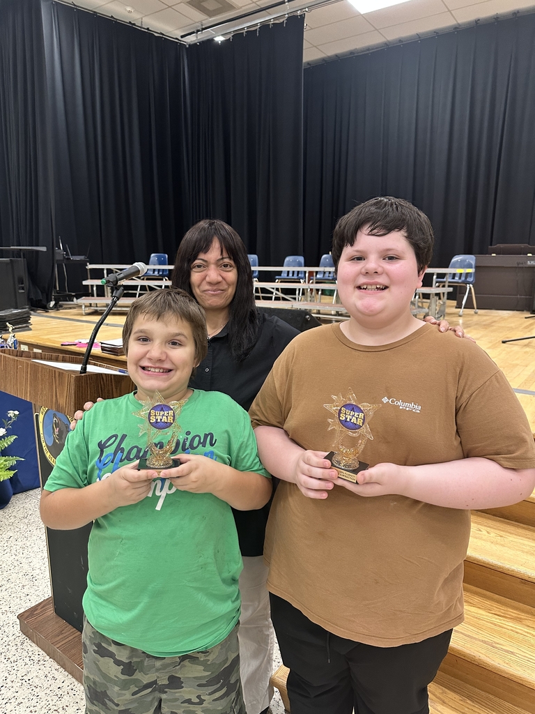 Male students, Nathan and Billy hold up trophies with Mrs. Youssef, standing and smiling behind them.
