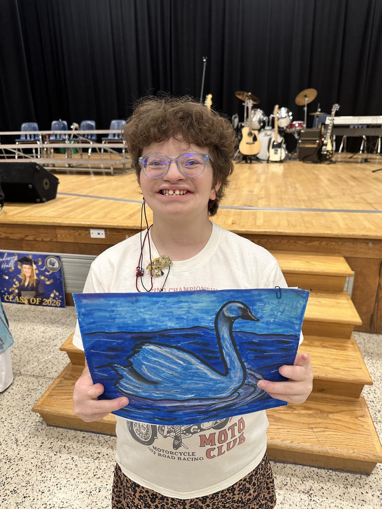 A female student, Willow smiles and holds up a painting of a swan.