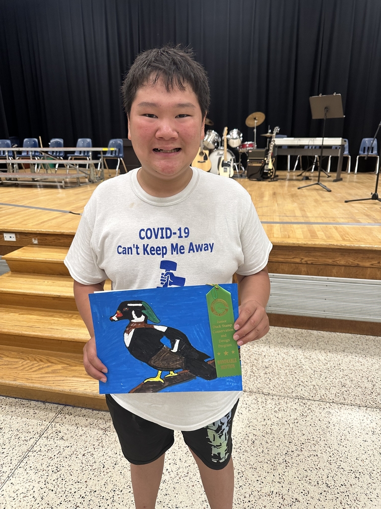 Tristian smiles for the camera as he holds up a painting of a duck.