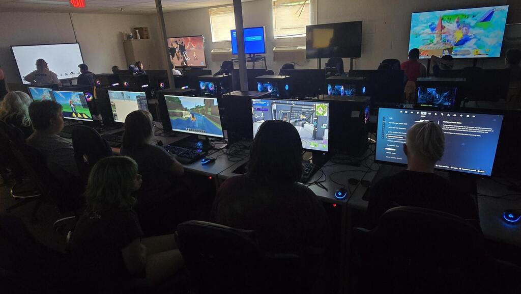 Camp participants face away from the camera as they participate in esports. They are all looking at computer monitors.