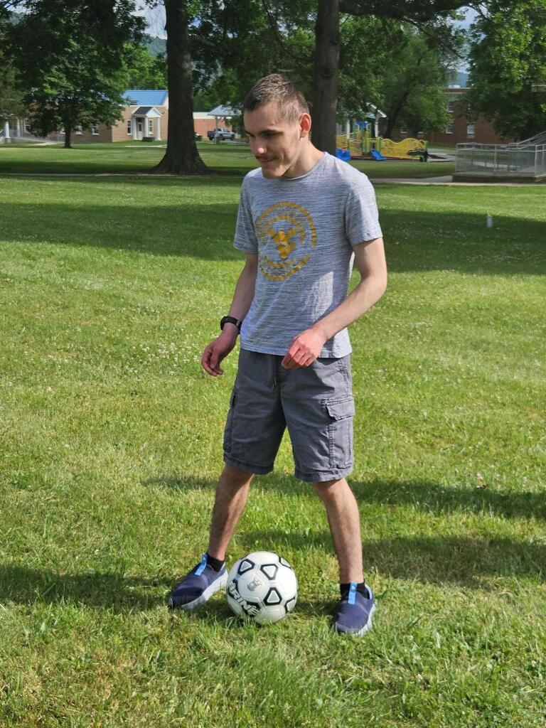Hunter, a male camp participant stands with a white and black soccer ball between his feet practicing a soccer drill.
