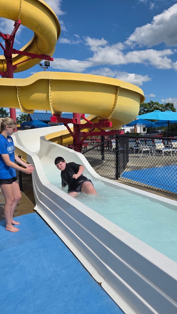 A male camp participant sits at the bottom of the white waterslide after he came down the slide.