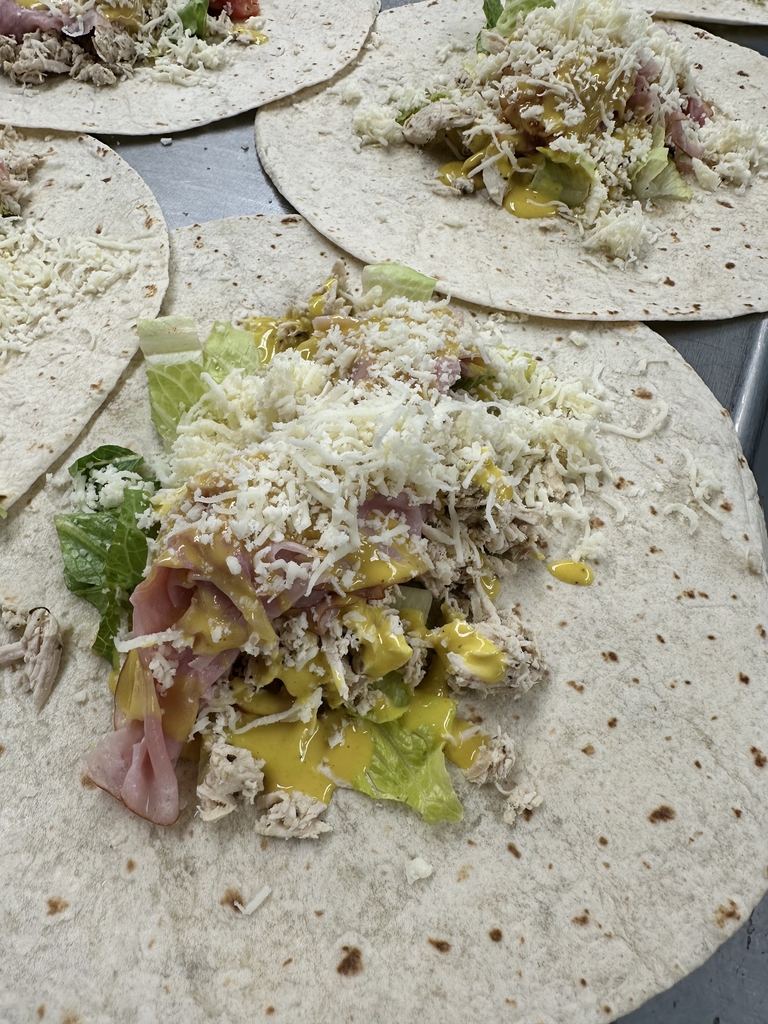 Chicken Cordon Bleu Wrap. A white tortilla is packed with grilled chicken, ham, mozzarella cheese, lettuce, and topped with honey mustard.