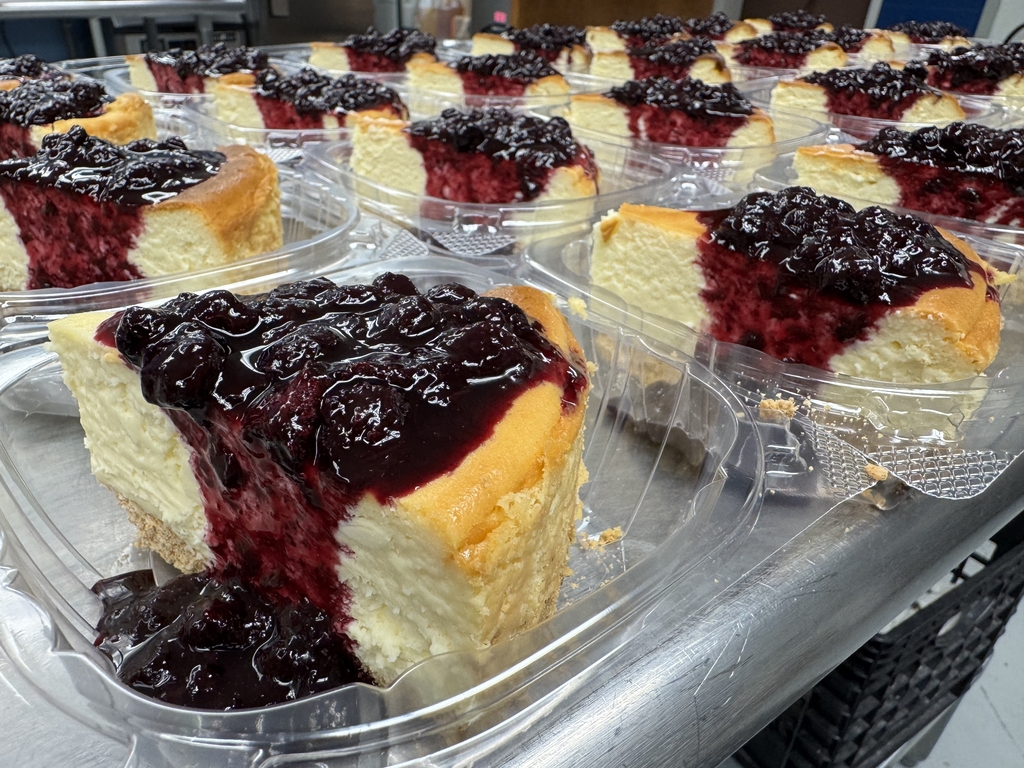 Lemon Blueberry Cheesecake. Slices on cheesecake with a blueberry sauce are in clear, plastic containers.