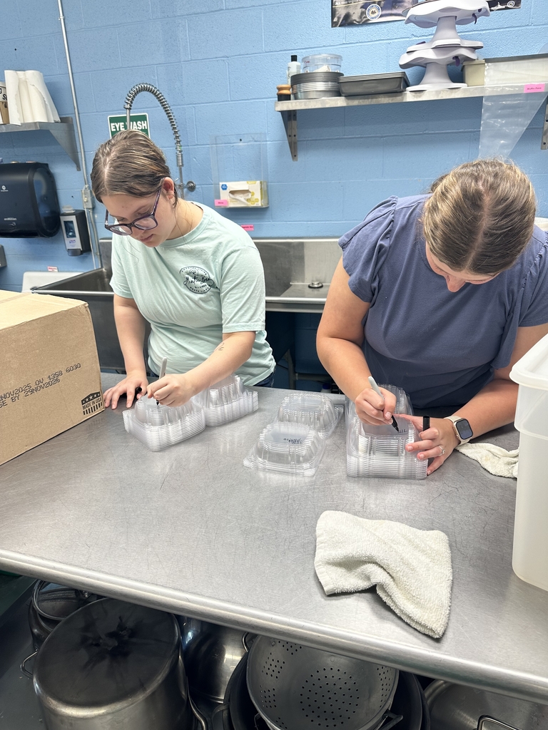 Bindi and Candace look down as they mark the dates on clear, plastic containers.
